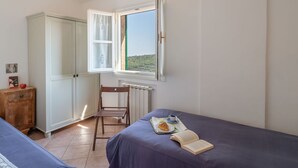 A bedroom with two beds, a wardrobe, a radiator, and a window with a view of greenery. - Beautiful private villa with WIFI, private pool, TV, terrace, pets allowed and panoramic view (Pietrabruna)