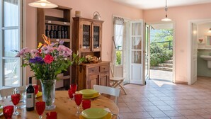 A dining area with a wooden table set for a meal, a vase of flowers, and a wine bottle. - Beautiful private villa with WIFI, private pool, TV, terrace, pets allowed and panoramic view (Pietrabruna)