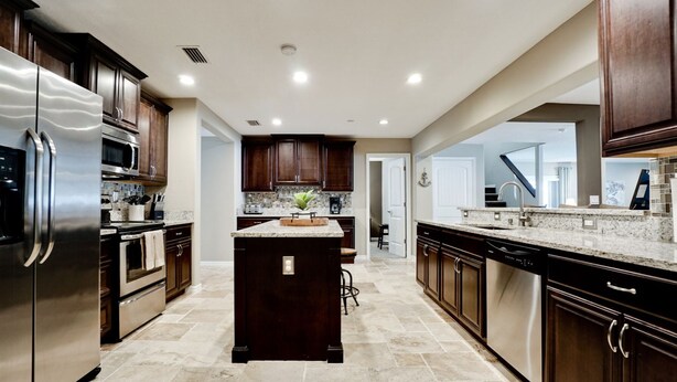A modern kitchen with dark wood cabinets, stainless steel appliances, and a central island. - Tropical Highlands - 6 BEDROOMS/3 Bathroom/2 King Masters/3800 sf/Large Htd Pool (Bradenton)
