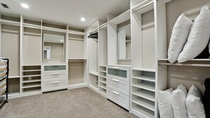A walk-in closet with multiple shelves, drawers, and hanging space, featuring a neutral color scheme and a mirror. - Tropical Highlands - 6 BEDROOMS/3 Bathroom/2 King Masters/3800 sf/Large Htd Pool (Bradenton)