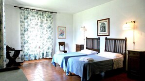 Een slaapkamer met twee bedden, een houten hoofdbord, een nachtkastje, een lamp en een lijst met een afbeelding aan de muur.