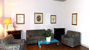 Een woonkamer met gestreepte banken, een salontafel, een lamp en lijstjes met foto’s aan de muur.