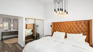 Une chambre à coucher avec un grand lit, une coiffeuse avec un miroir et un lustre moderne.