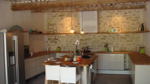 Eine Küche mit Steinwand, Holzausstattung und einem Edelstahl-Kühlschrank.