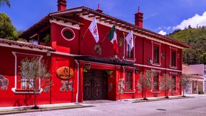 A red colonial-style building with a large wooden door, multiple windows, and flags. - Hotel Boutique & Spa Casa Colorada (Patzcuaro)