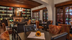 A dining area with a fireplace, leather chairs, and a table with a sunflower centerpiece. - Hotel Boutique & Spa Casa Colorada (Patzcuaro)