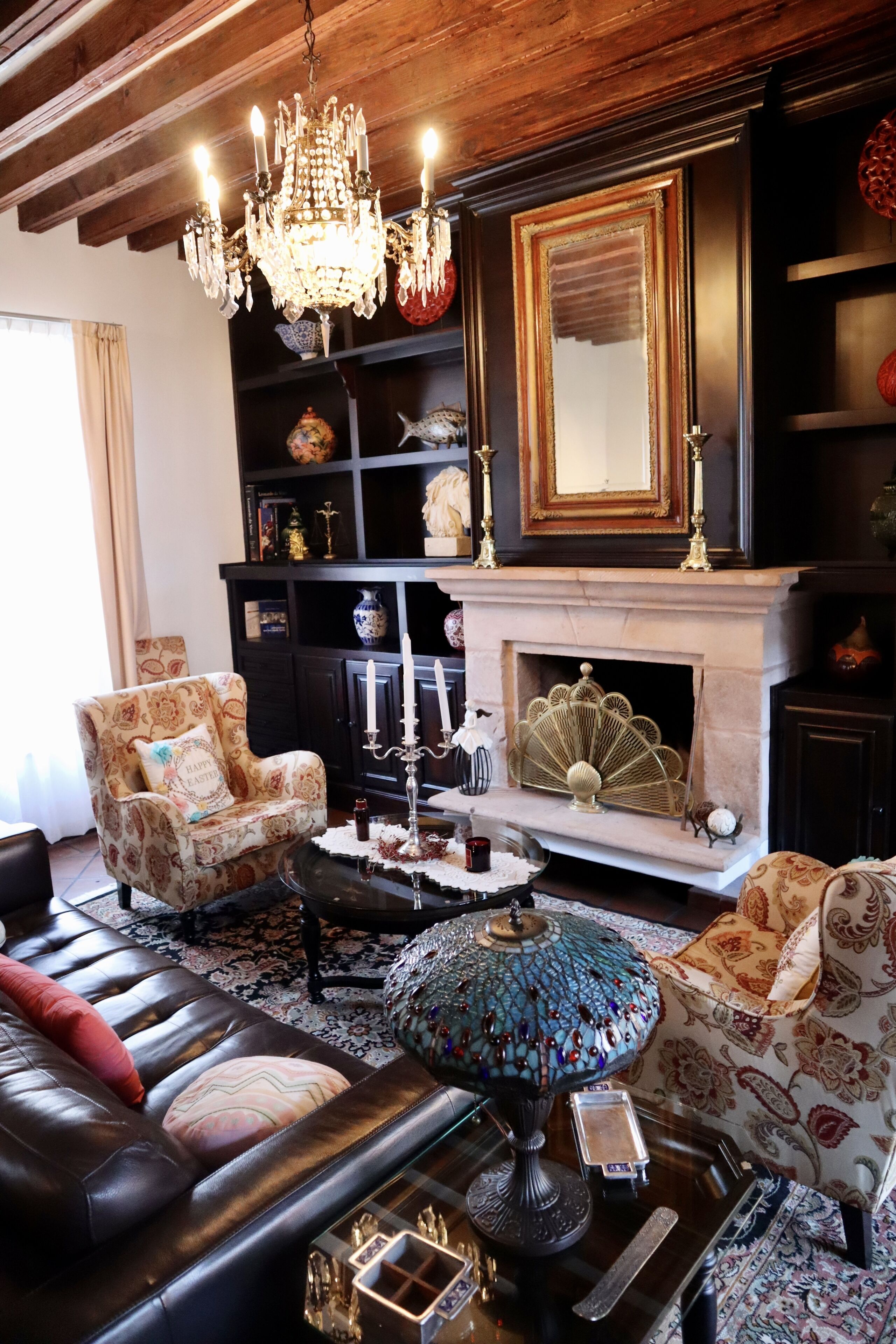 A traditional living room with a fireplace, a chandelier, and a patterned armchair.
