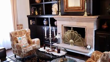 A traditional living room with a fireplace, a chandelier, and a patterned armchair.