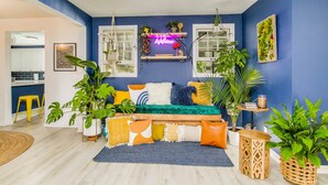 A modern living room with a blue accent wall, a green sofa, and various plants. - NAS, Pensacola Beach, Pool House -20mins to both beaches (Pensacola)