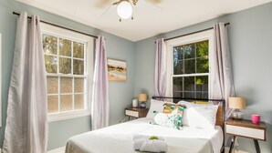 A neatly made bed with a white comforter and pillows, two bedside tables with lamps, and a window with curtains. - NAS, Pensacola Beach, Pool House -20mins to both beaches (Pensacola)