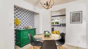 A dining area with a round table, black chairs, a green sideboard, and a patterned wallpaper. - NAS, Pensacola Beach, Pool House -20mins to both beaches (Pensacola)