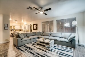 Un salon moderne avec un canapé d’angle, une table basse et un tapis à motifs.