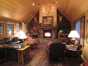 Cozy living room with a fireplace, leather sofa, and mounted deer heads.