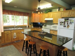 Enjoy cooking in this well-equipped kitchen with a central island, refrigerator, and microwave.