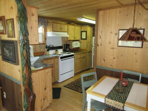 Enjoy meals in this cozy kitchen with a central stove, dining table, and comfortable chair.
