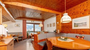 Een houten cabin met een eettafel, stoelen en een keukenhoek.