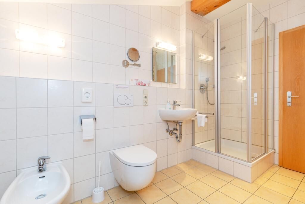 Ein modernes Badezimmer mit Toilette, Bidet, Waschbecken und einer Duschkabine.