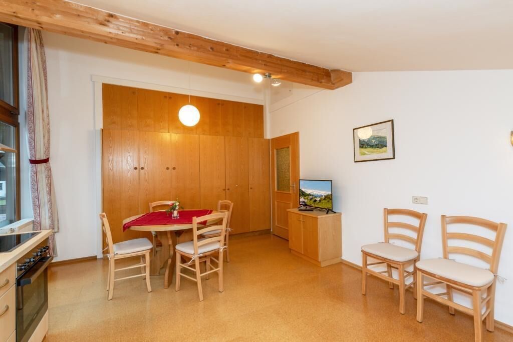 A dining area with wooden furniture, a TV, and a window with curtains.