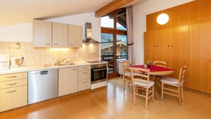 Een moderne keuken met witte kasten, een ingebouwde oven en een eethoek met houten stoelen en een rode tafelkleed.