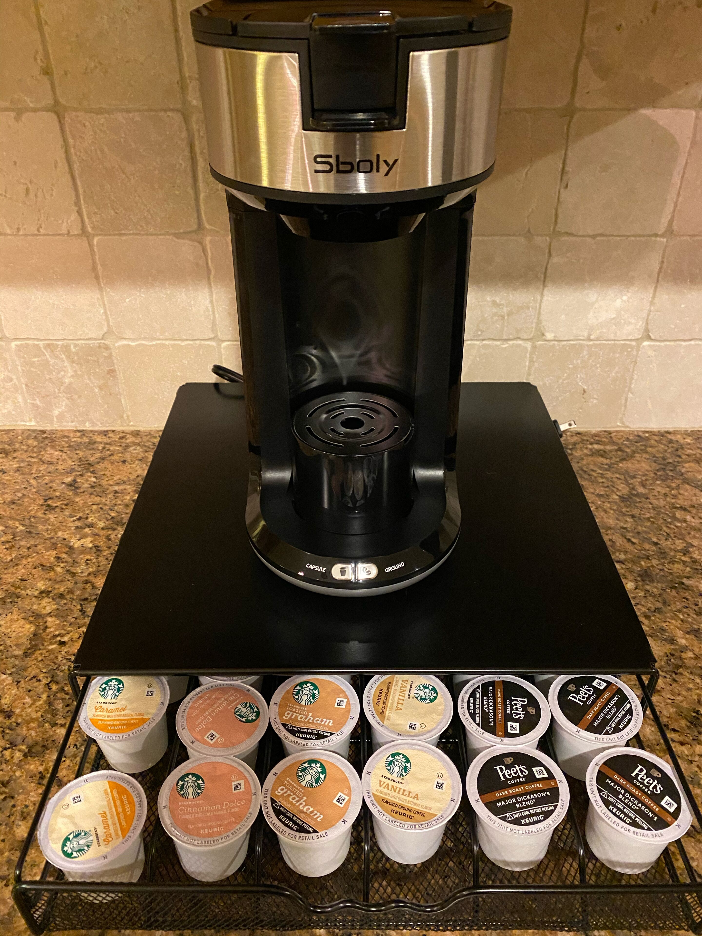 Une machine à café dotée d’un bac de récupération et d’un support pour les capsules de café situé en dessous.