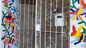 A building entrance with a colorful floral mural, a metal gate, and a tiled ground with a geometric pattern. - Villas Velarde + Pool + Great Location (cozumel)