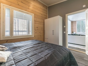 A bedroom with a bed, a wardrobe, and a window with blinds.