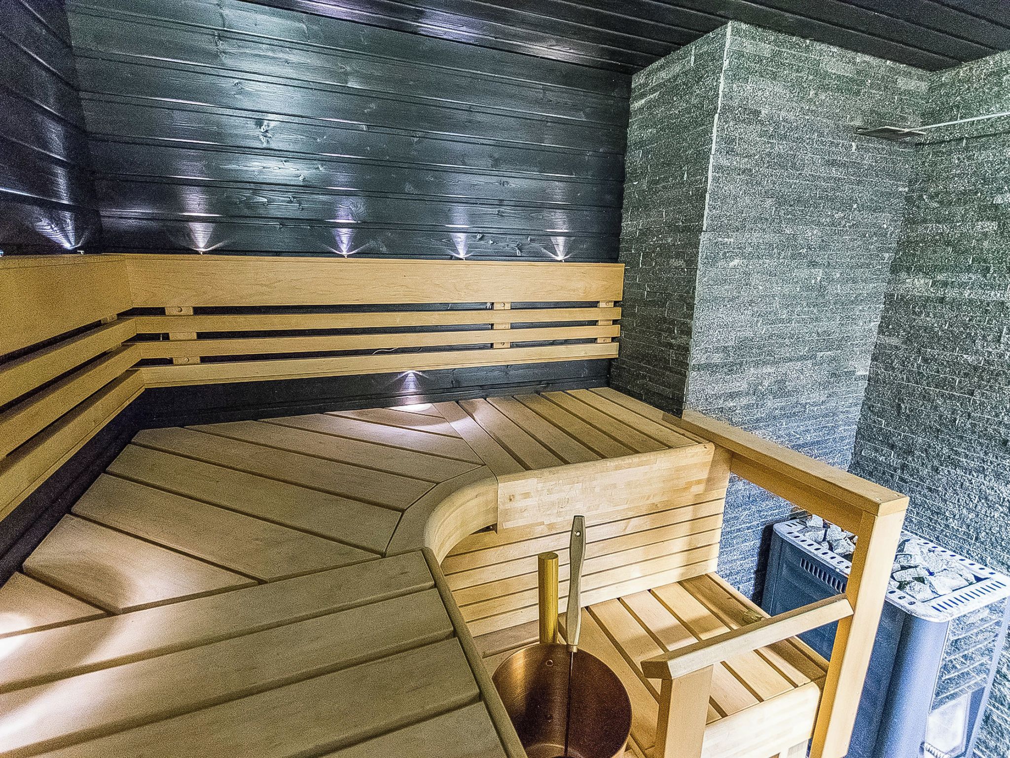 Un sauna avec un banc en bois, un banc doté d’un dossier et un mur à la surface texturée.