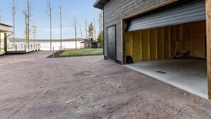 A building with a garage door open, a small shed, and a wooden deck with a view of a lake. - Metsola by Interhome (Ruovesi)