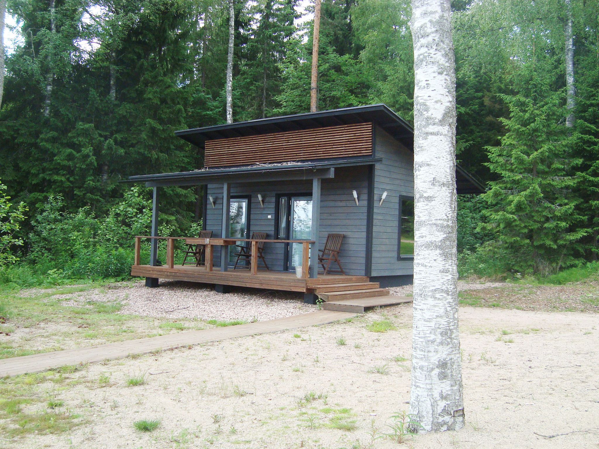 A cabin with a wooden deck, built-in seating, and a view of the surrounding forest.