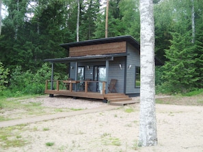 A cabin with a wooden deck, built-in seating, and a view of the surrounding forest.