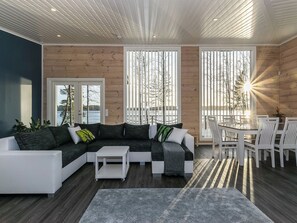 A modern living room with a sectional sofa, a coffee table, and a dining area with chairs and a table. - Metsola by Interhome (Ruovesi)