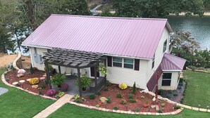 A house with a covered porch, a small attached garage, and a well-maintained garden with various plants and flowers. - Discover Your Convenient Paradise: Minutes from I-65, Cullman, and Boat Launch (Cullman)