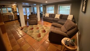 A spacious living room with a sectional sofa, a recliner, and a coffee table. A kitchen is visible in the background, and there is a dining area with a table and chairs. - Discover Your Convenient Paradise: Minutes from I-65, Cullman, and Boat Launch (Cullman)