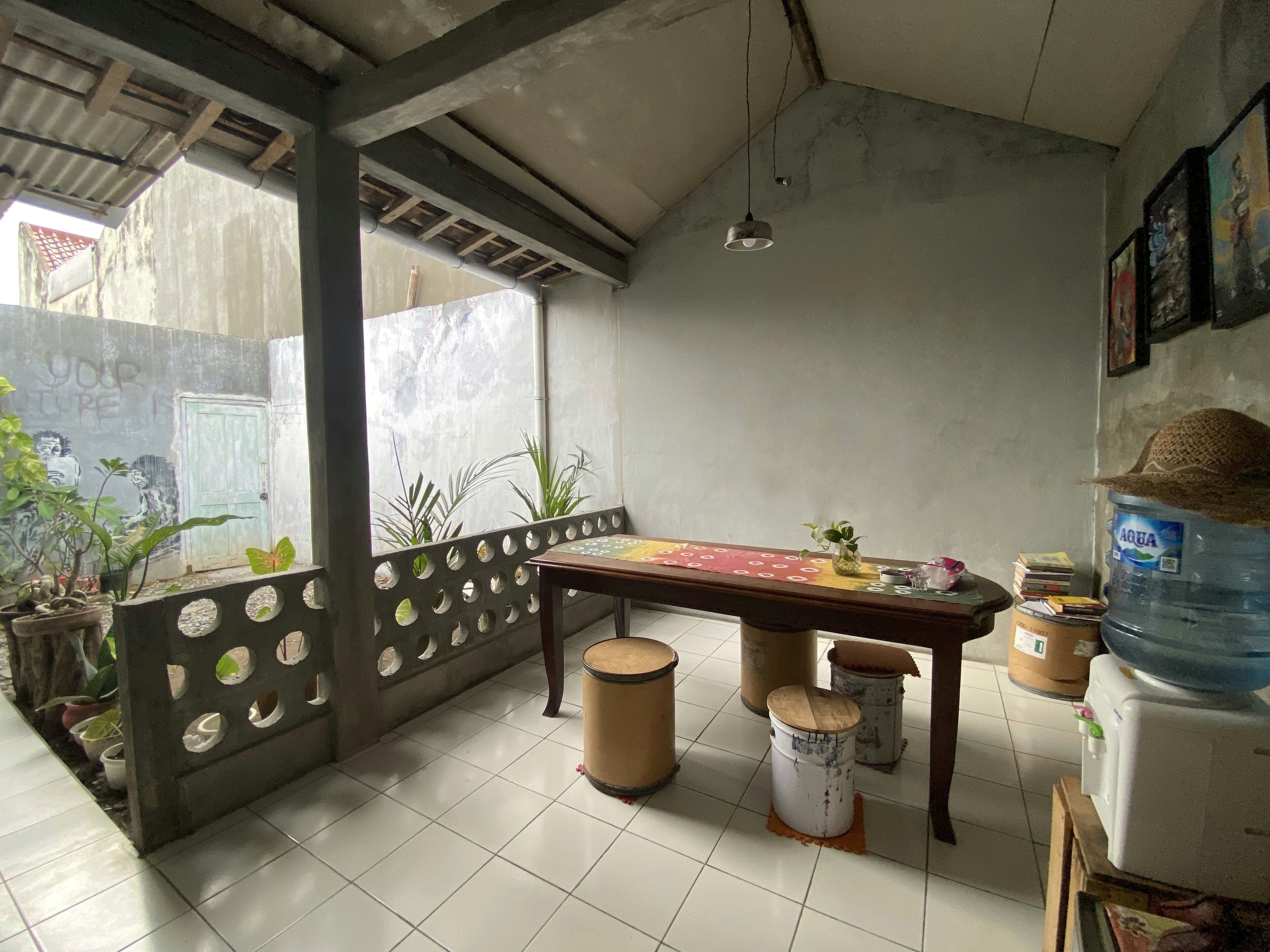 A small, enclosed patio area with a table and chairs, a water dispenser, and a few potted plants.