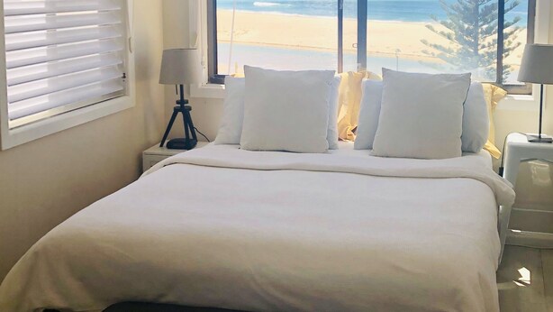 Ein Schlafzimmer mit einem großen Bett, einem Deckenventilator und Blick auf den Strand.