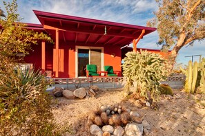 A red building with a covered patio, two green chairs, and a cactus in the foreground. - Chucks cabin Joshua Tree region, your desert Oasis (TWENTYNIN PLAMs)