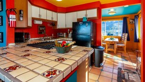A kitchen with a tiled island, a black refrigerator, and a window with a view. - Chucks cabin Joshua Tree region, your desert Oasis (TWENTYNIN PLAMs)