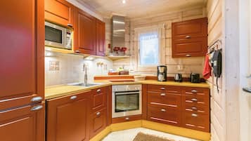 Eine kleine Küche mit Holzausstattung, einer Mikrowelle, einem Backofen und einer Kaffeemaschine.