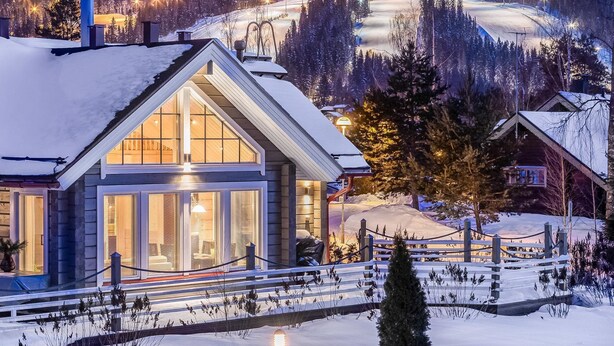A snow-covered lodge with large windows and a wooden exterior.