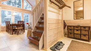 A wooden staircase leading to a second floor, a dining area with chairs and a table, and a storage unit with baskets.