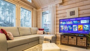 A cozy living room with a sectional sofa, a flat-screen TV, and a large window.