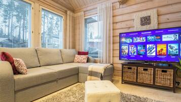 Ein gemütliches Wohnzimmer mit einem Ecksofa, einem Flachbildfernseher und einer Holzbalkendecke.