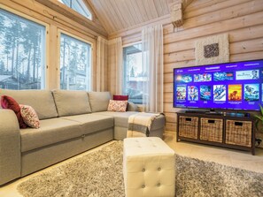 Una sala de estar acogedora con un sofá seccional, un televisor de pantalla plana y techo de madera.