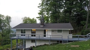 Une maison à deux étages avec un balcon, une cheminée et une petite terrasse.
