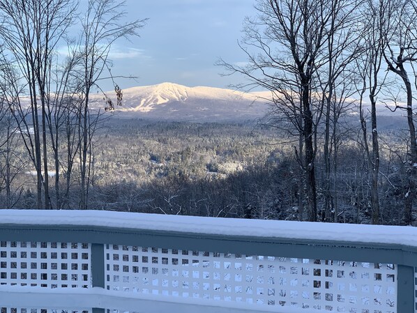 Un paysage enneigé, avec une montagne en arrière-plan et une clôture blanche au premier plan.