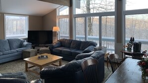 Un salon spacieux doté d’une grande fenêtre, d’un téléviseur à écran plat et d’une table basse en bois.