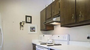 Une cuisine avec des appareils électroménagers blancs, des meubles de rangement en bois foncé et deux tableaux encadrés accrochés au mur.