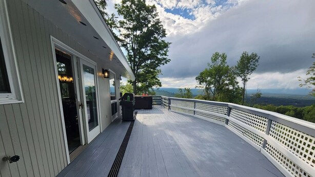 Une terrasse dotée d’une balustrade blanche, d’une porte-fenêtre coulissante et offrant une vue sur le paysage.