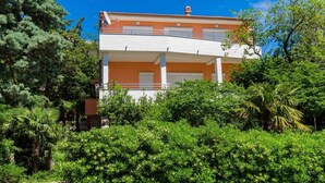 Un immeuble de deux étages doté d’un balcon et d’un jardin à l’avant.