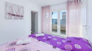 Une chambre à coucher avec un lit, un tableau et un balcon avec des rideaux.